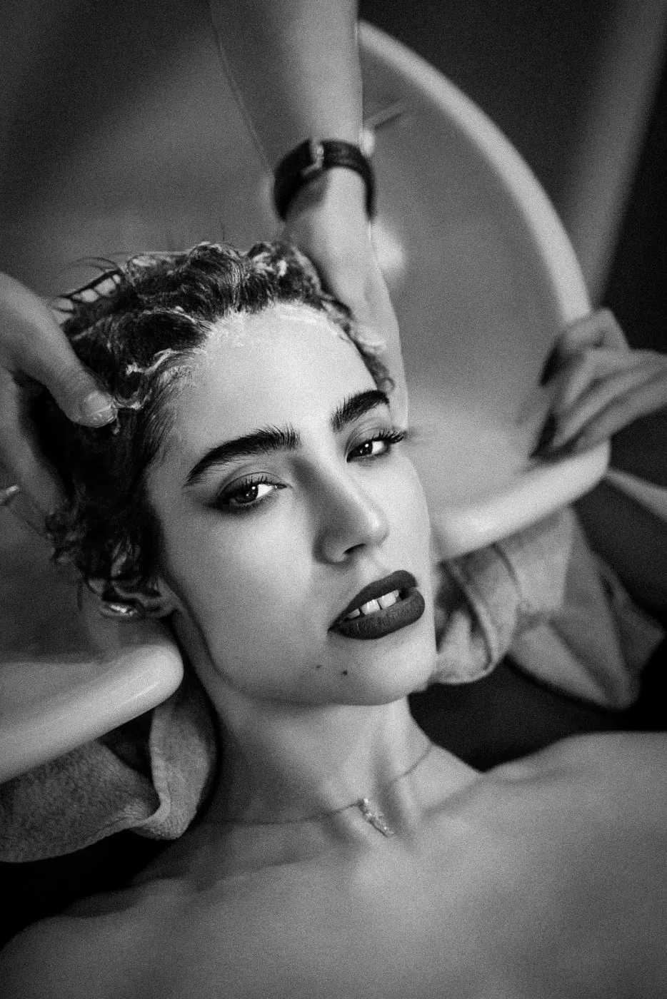 Hair being washed at the basin - close on her face, hands working her scalp.